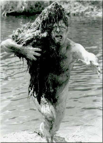 Man during the 1969 Woodstock concert rising out of the water covered with moss and gesturing menacingly